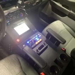 Photo of Interior view of an ambulance driver’s cab showing the center control console, radio equipment, and equipment mounts