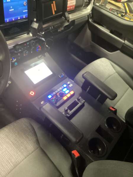Photo of Interior view of an ambulance driver’s cab showing the center control console, radio equipment, and equipment mounts